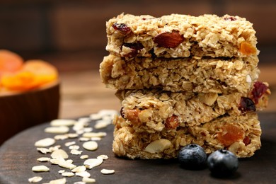 Photo of Stack of tasty granola bars on table, closeup. Space for text