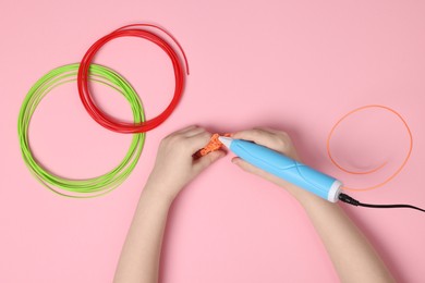 Photo of Boy drawing with stylish 3D pen on pink background, top view