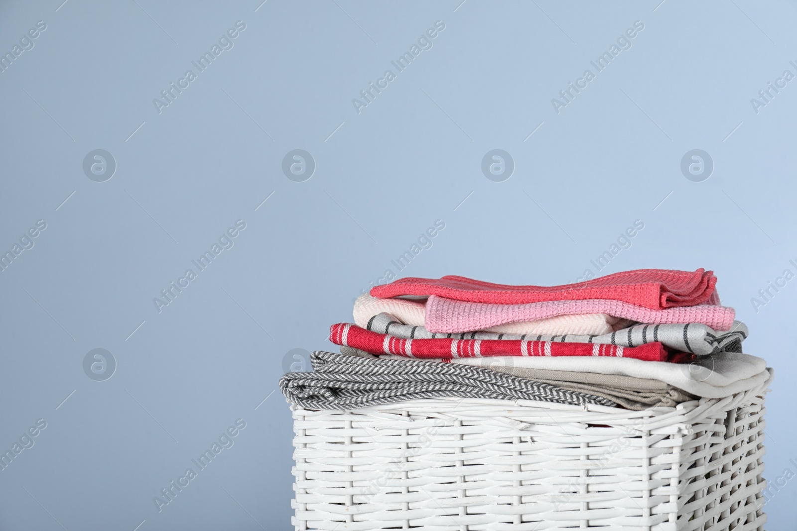 Photo of Wicker laundry basket with clean towels on color background, closeup. Space for text