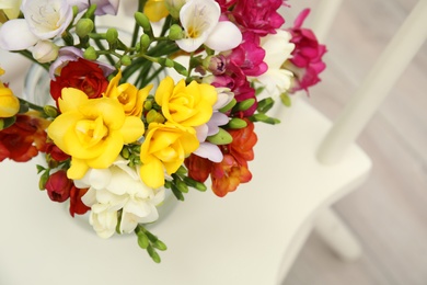 Photo of Beautiful spring freesia flowers on chair, view from above. Space for text