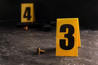 Photo of Shell casings and evidence marker on black slate table, closeup. Crime scene