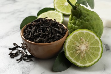 Photo of Dry bergamot tea leaves and fresh fruits on white marble table