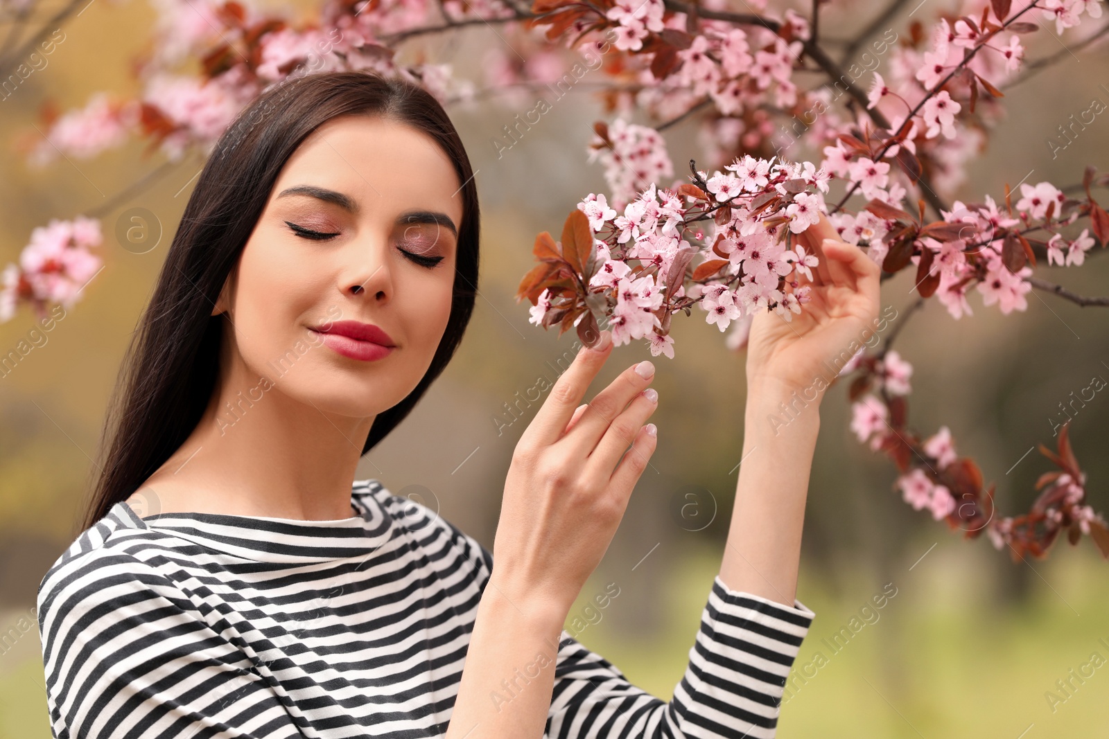 Photo of Pretty young woman near blooming tree in park. Spring look