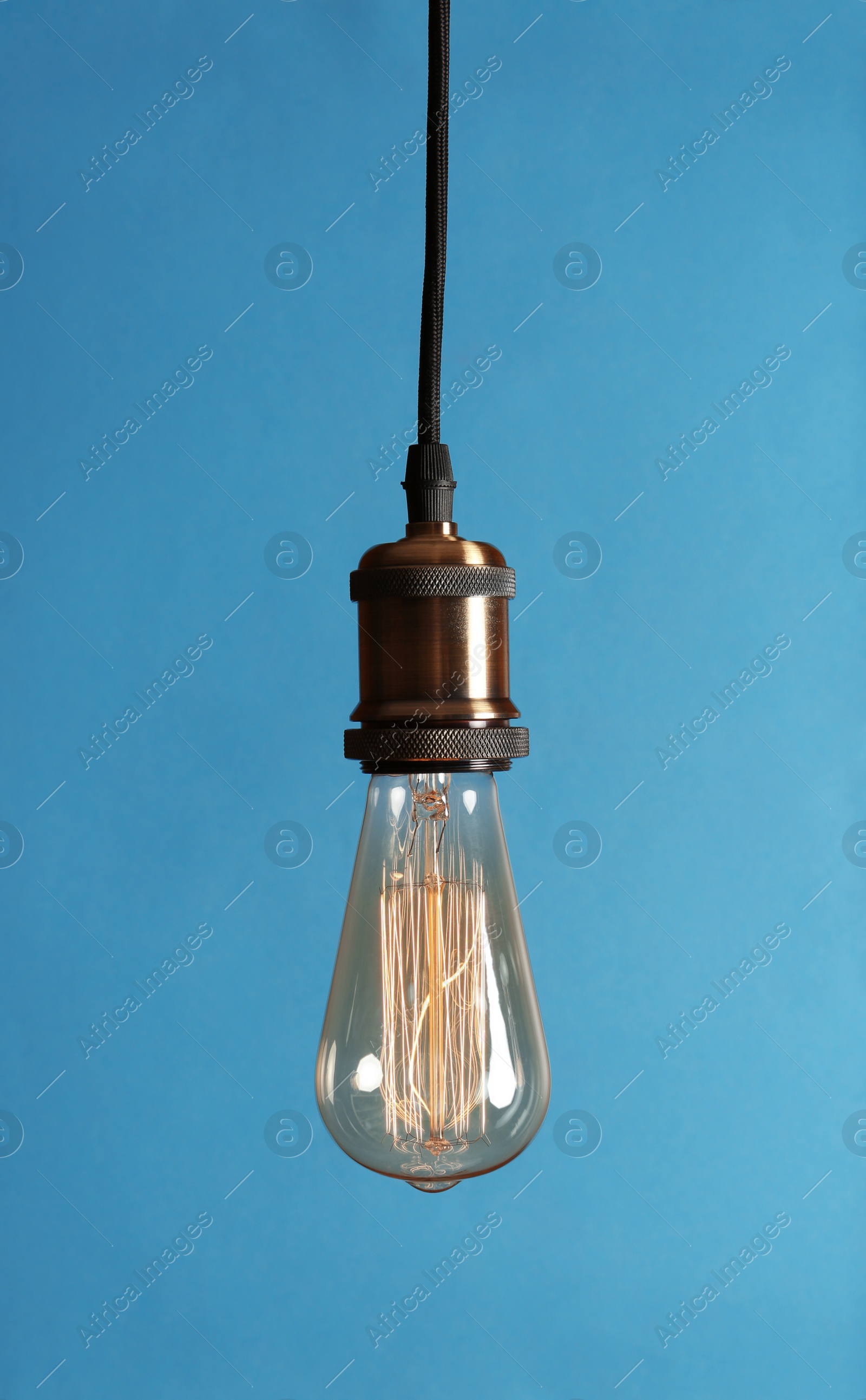 Photo of Hanging modern lamp bulb against blue background