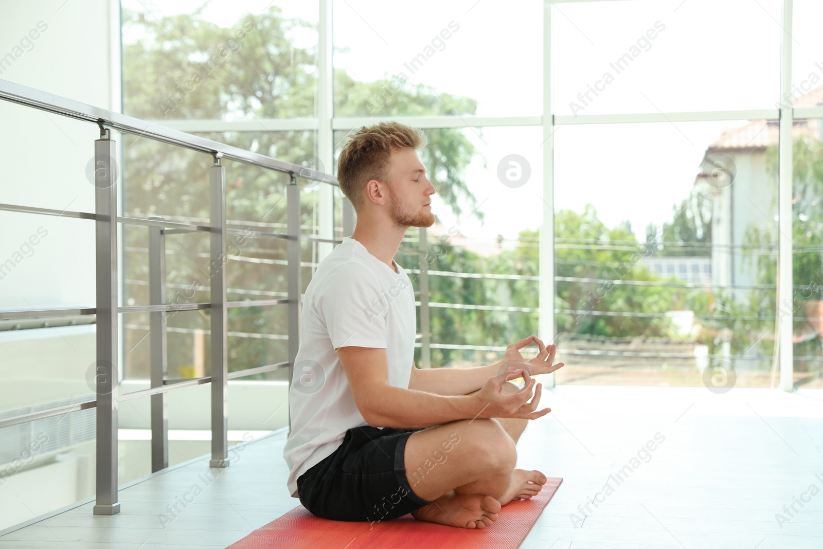 Photo of Handsome young man practicing zen yoga indoors