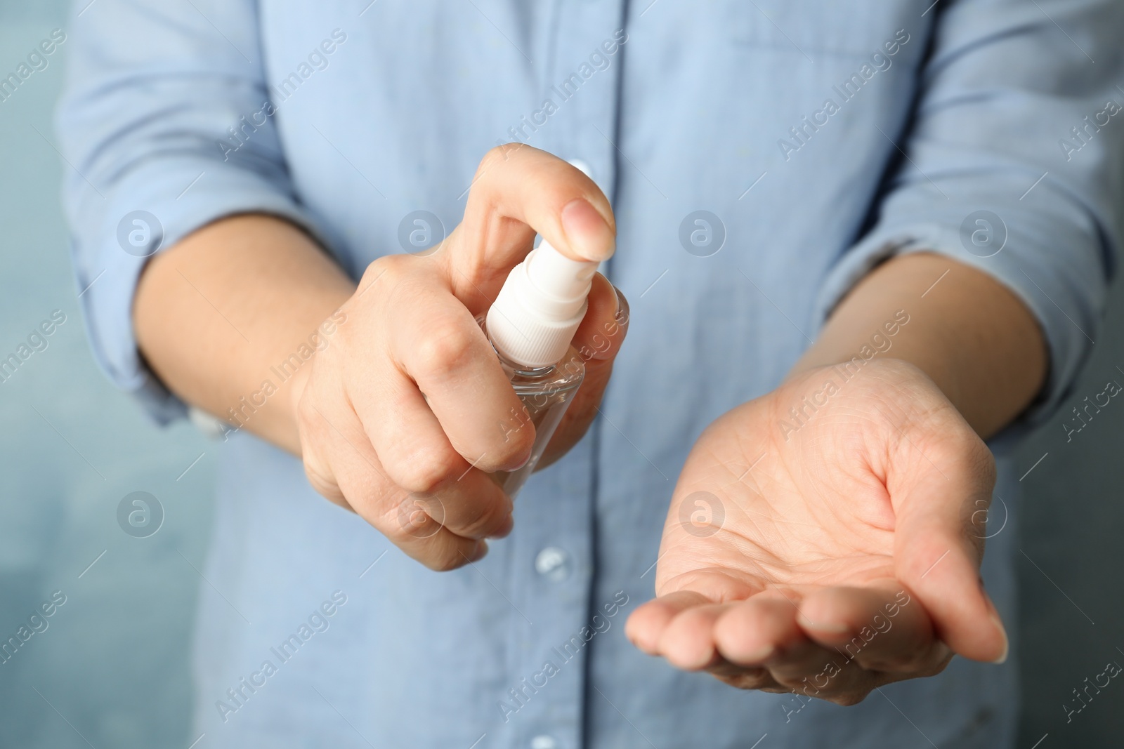 Photo of Woman spraying antiseptic onto hand, closeup. Virus prevention