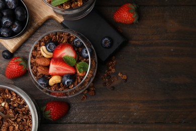 Photo of Tasty granola, berries and nuts on wooden table, flat lay. Space for text