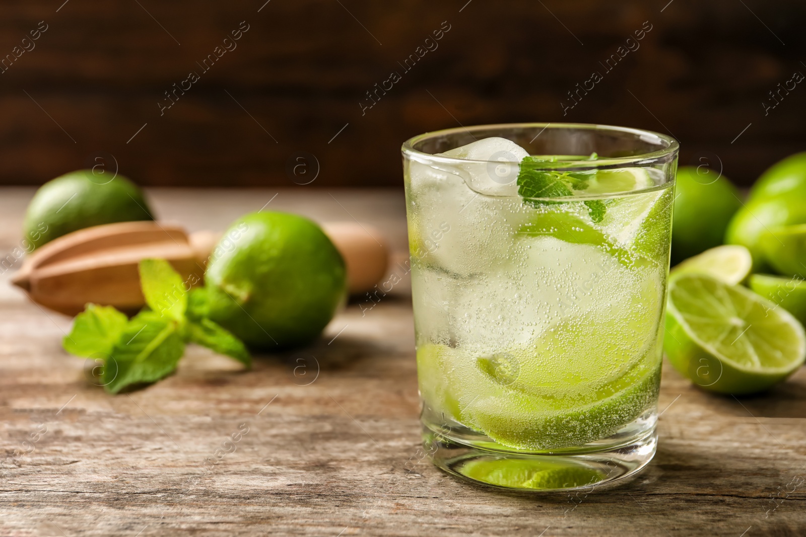 Photo of Refreshing beverage with mint and lime in glass on table