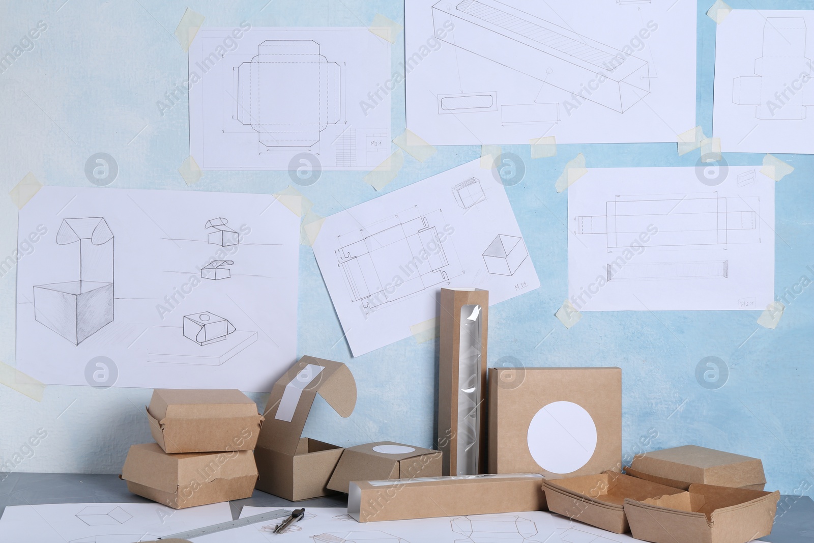 Photo of Creating packaging design. Drawings, boxes and stationery on table, closeup