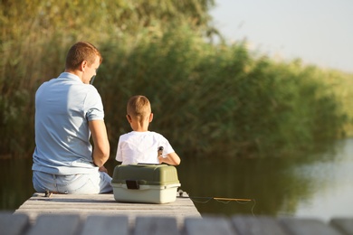 Dad and son fishing together on sunny day. Space for text