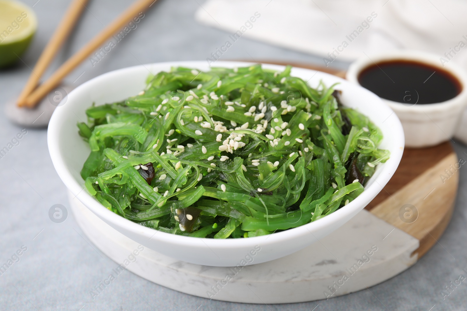 Photo of Tasty seaweed salad in bowl served on gray table, closeup