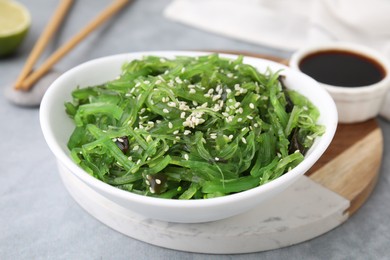 Photo of Tasty seaweed salad in bowl served on gray table, closeup