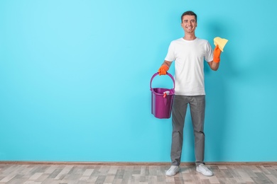 Man with cleaning supplies near color wall