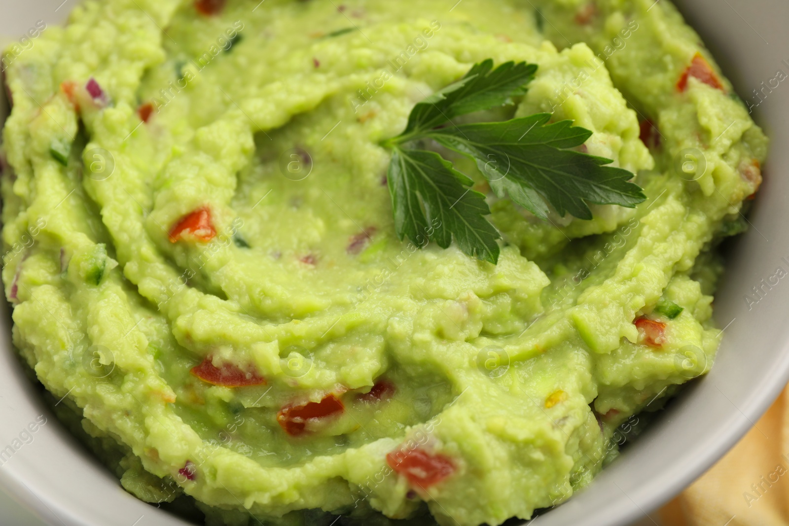 Photo of Bowl of delicious guacamole with parsley, closeup