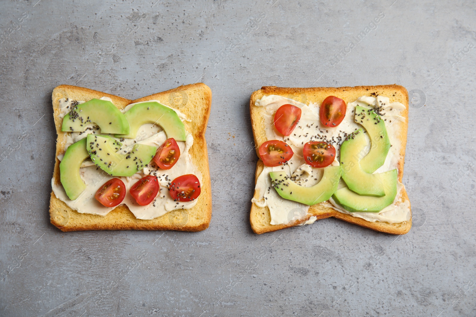 Photo of Tasty toasts with avocado, cherry tomatoes and chia seeds on grey background, top view