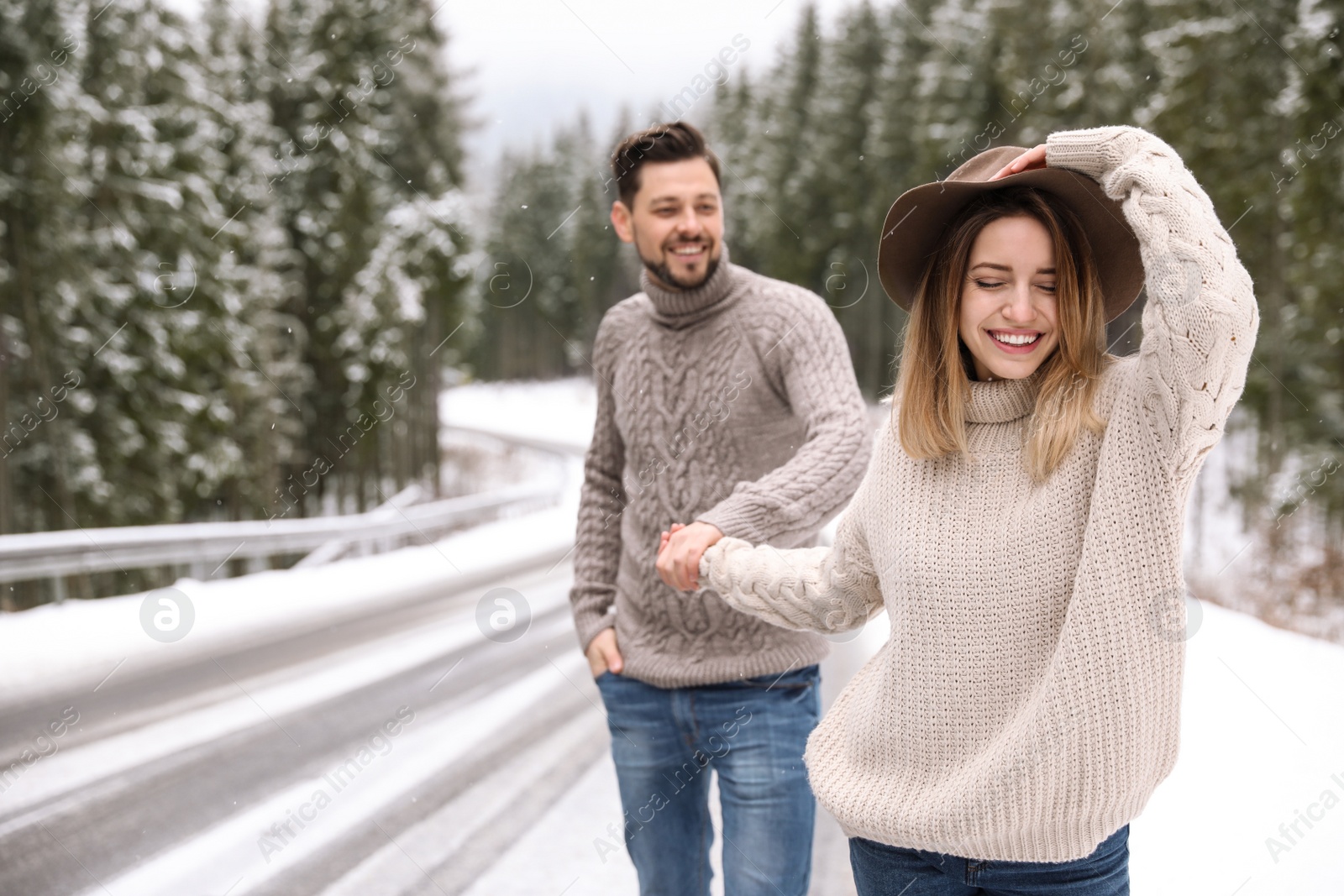 Photo of Couple walking near snowy forest, space for text. Winter vacation