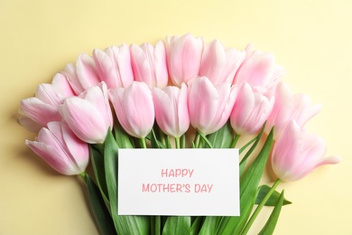 Beautiful tulips and greeting card with phrase "Happy Mother's Day" on color background