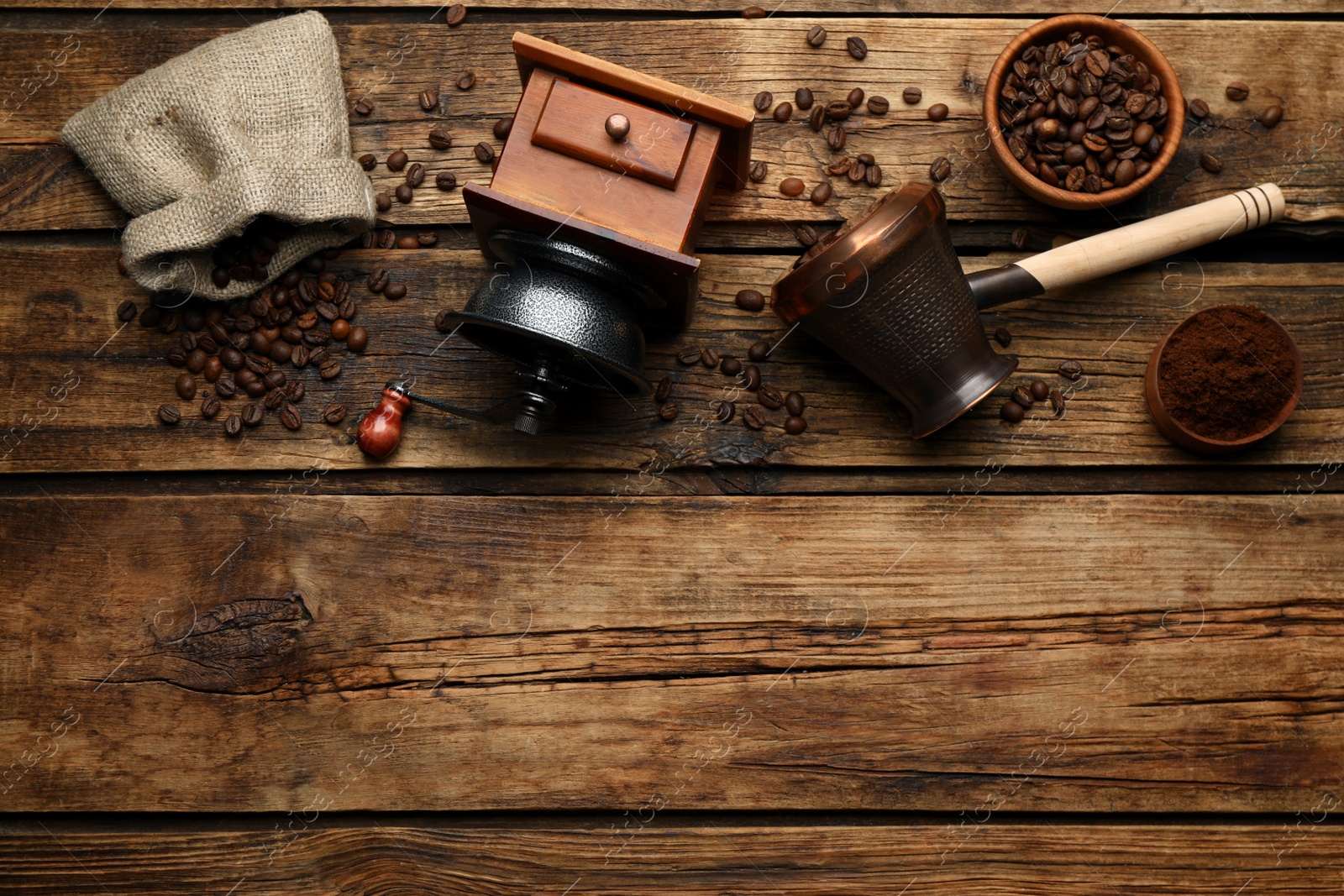 Photo of Vintage manual coffee grinder, beans, powder and jezve on wooden table, flat lay. Space for text