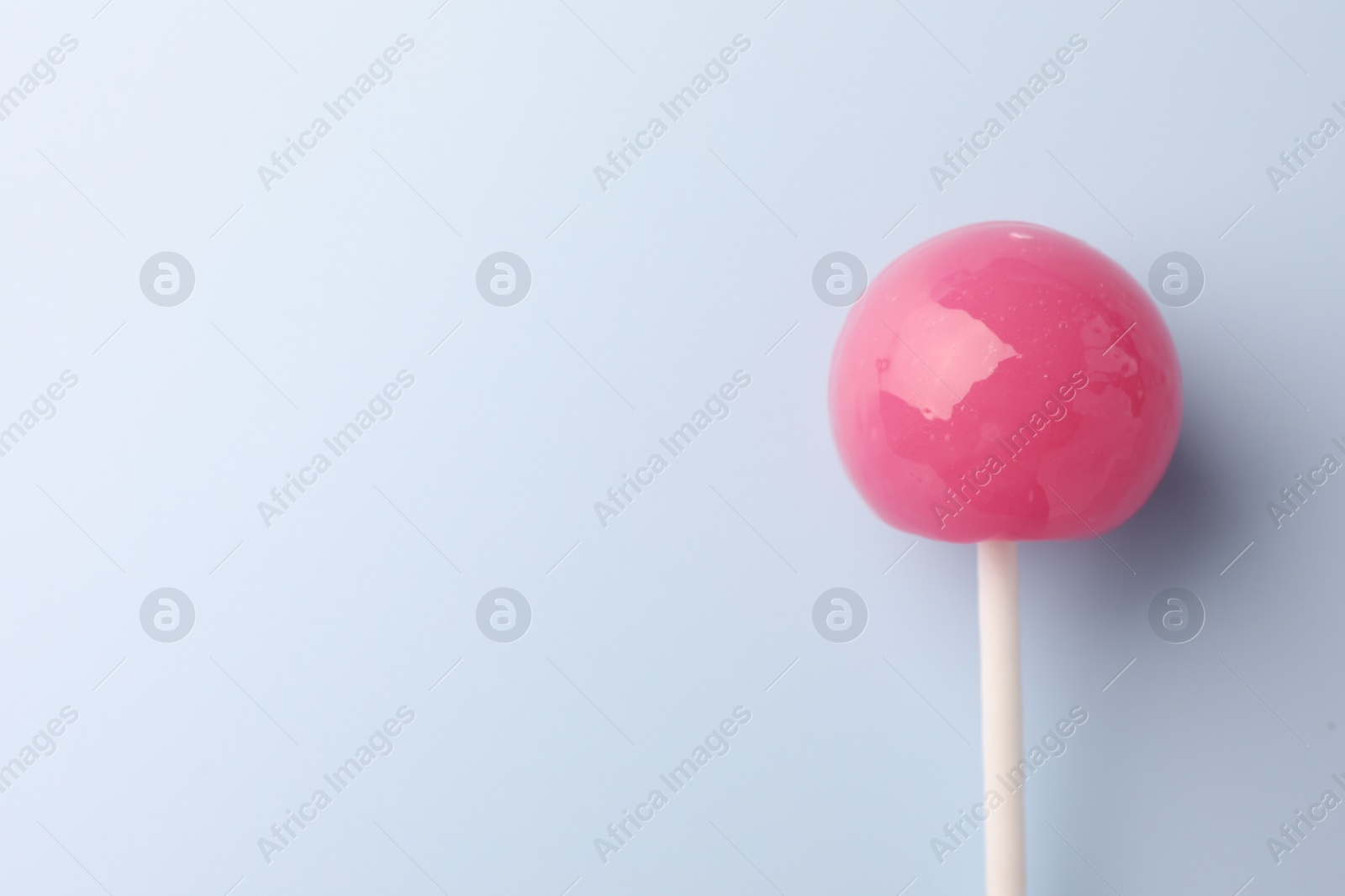 Photo of Tasty lollipop on light blue background, top view. Space for text