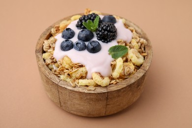 Photo of Tasty granola, yogurt and fresh berries in bowl on pale brown background, closeup. Healthy breakfast