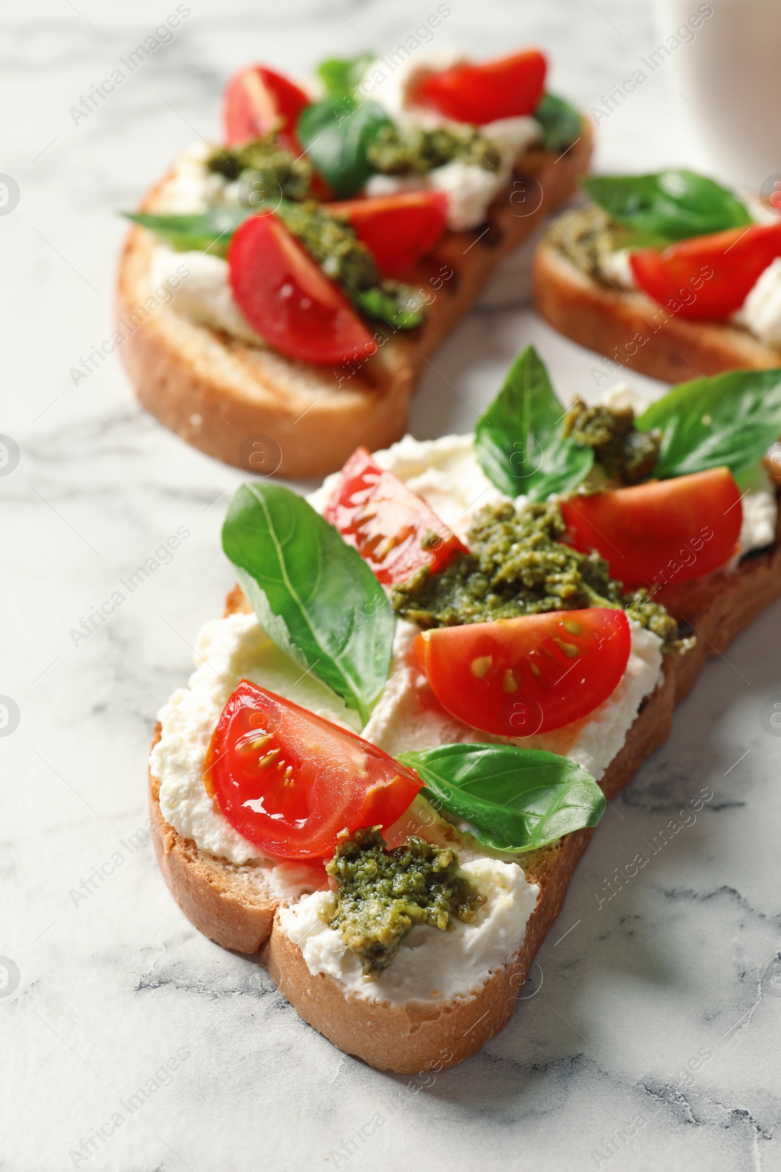 Photo of Toasted bread with tasty cream cheese and tomatoes on marble table