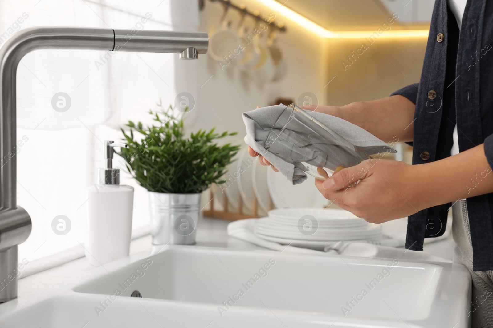 Photo of Woman wiping glass with towel in kitchen, closeup