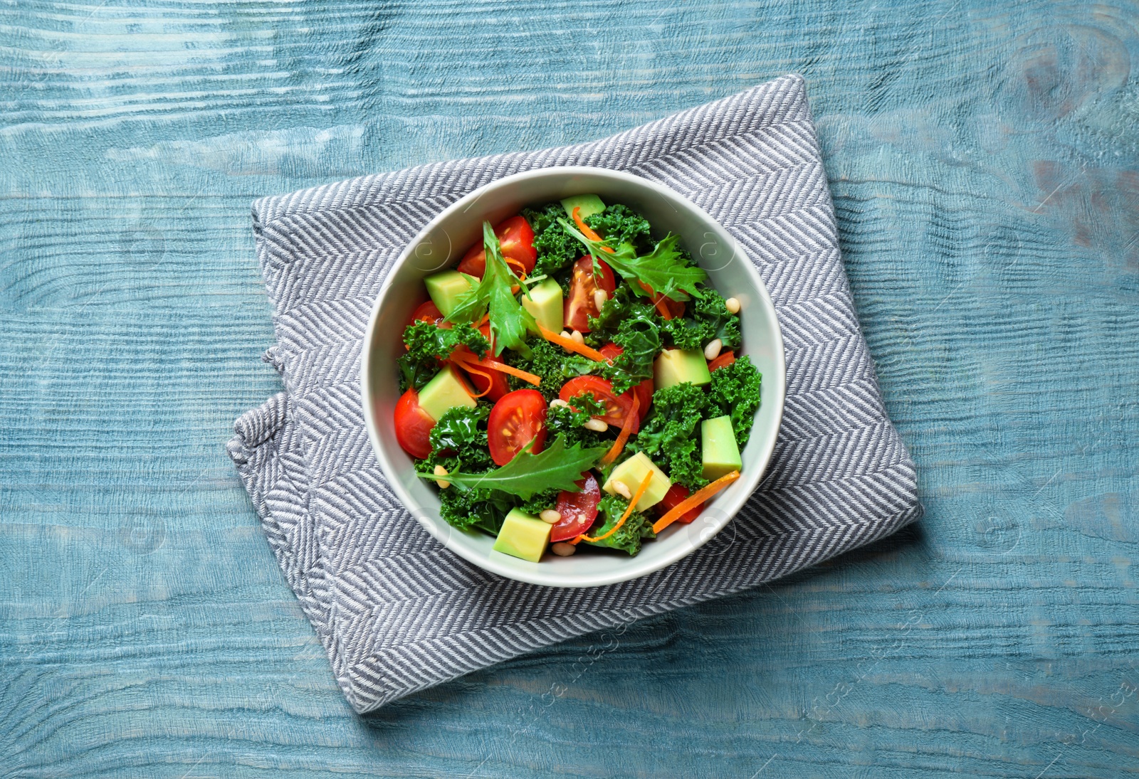 Photo of Tasty fresh kale salad on light blue wooden table, flat lay