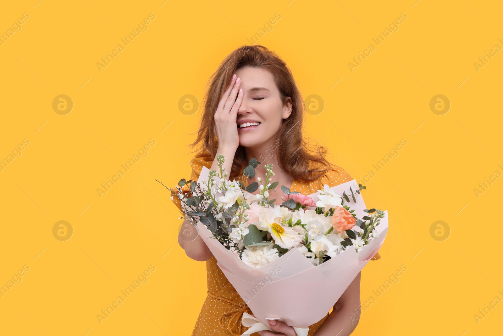 Photo of Happy woman with bouquet of beautiful flowers on yellow background