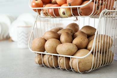 Container with potatoes and onions on grey kitchen counter. Orderly storage