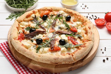 Photo of Tasty pizza with anchovies and ingredients on white wooden table