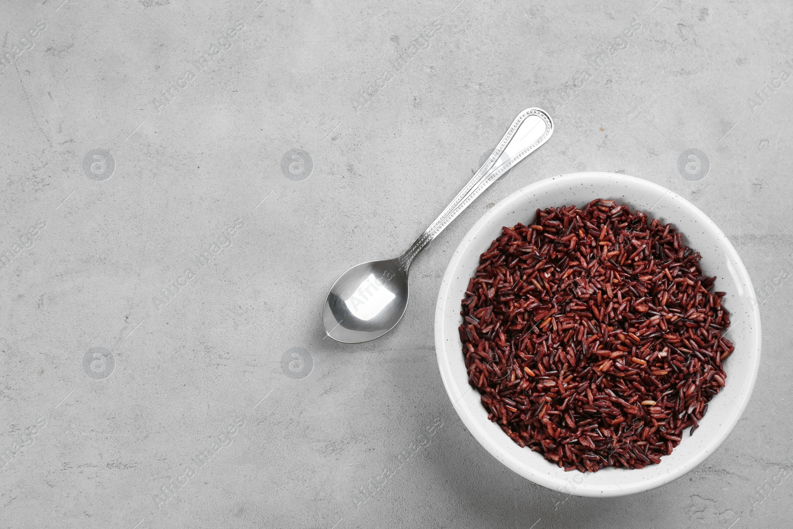 Photo of Tasty brown rice and spoon on light grey table, flat lay. Space for text