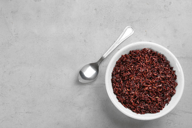 Tasty brown rice and spoon on light grey table, flat lay. Space for text