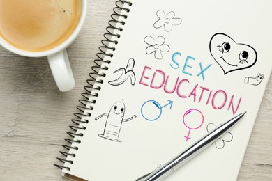 Image of Notebook with text Sex Education, male and female gender signs and different drawings on white wooden table, top view