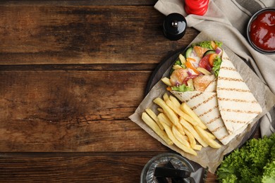 Delicious chicken shawarma and French fries served on wooden table, flat lay. Space for text