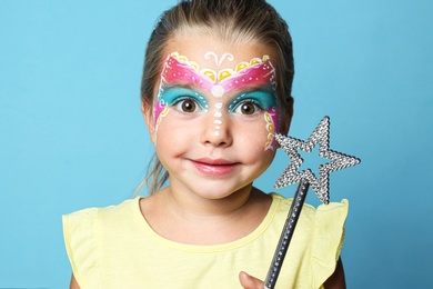 Photo of Cute little girl with face painting on blue background