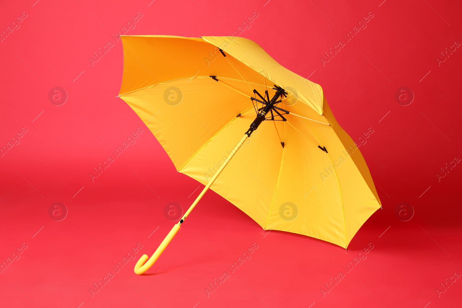 Photo of Stylish open yellow umbrella on red background