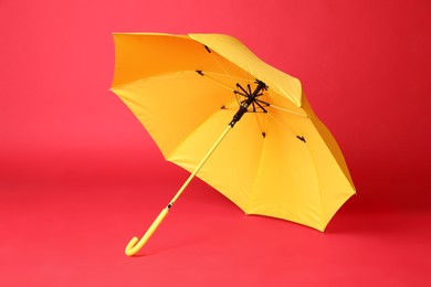 Photo of Stylish open yellow umbrella on red background