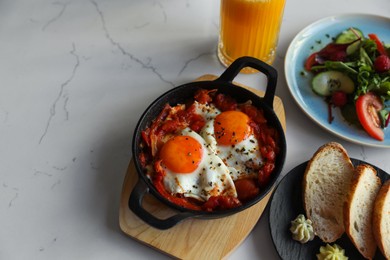 Photo of Tasty Shakshouka served on white marble table, above view. Space for text