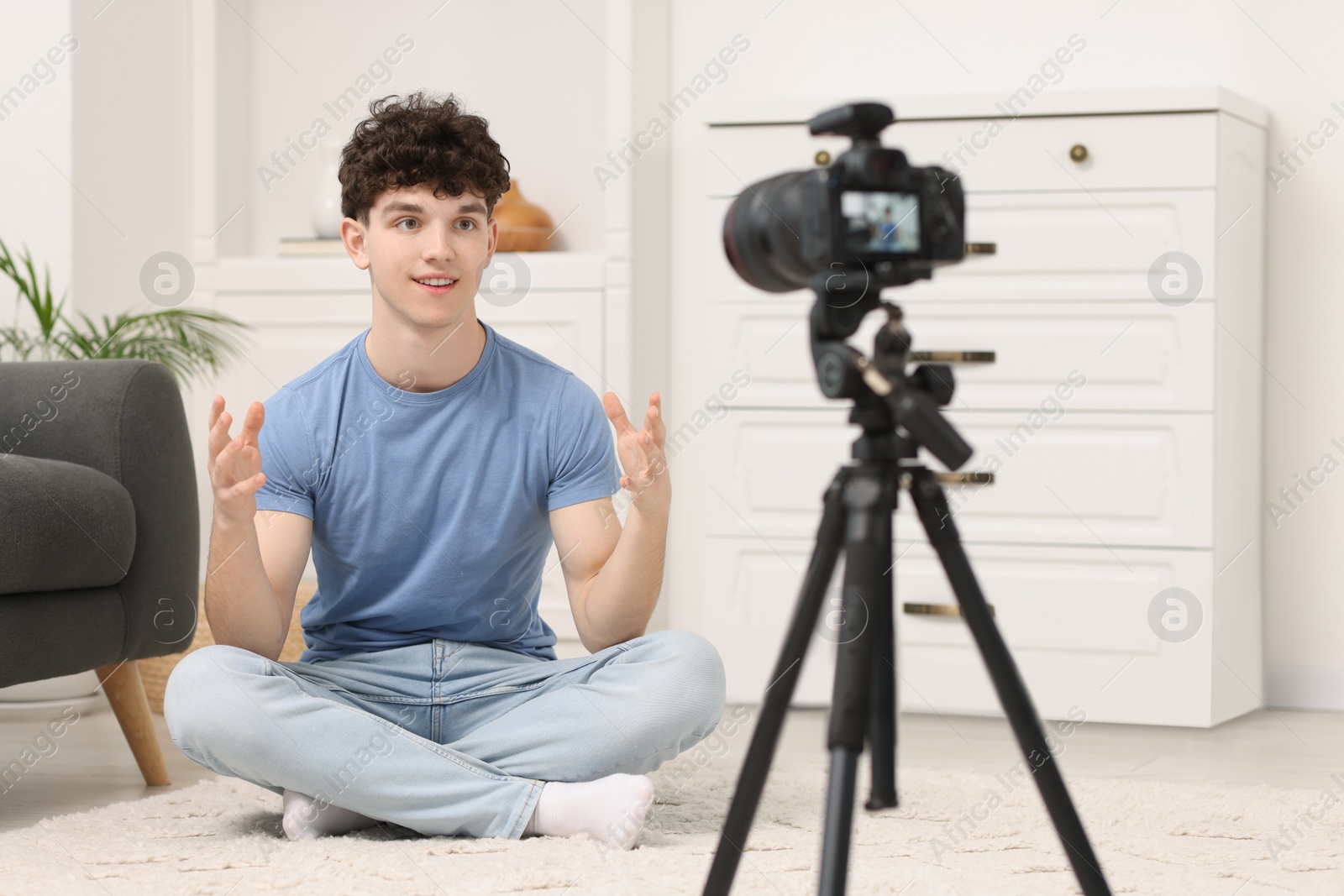 Photo of Smiling teenage blogger explaining something while streaming at home