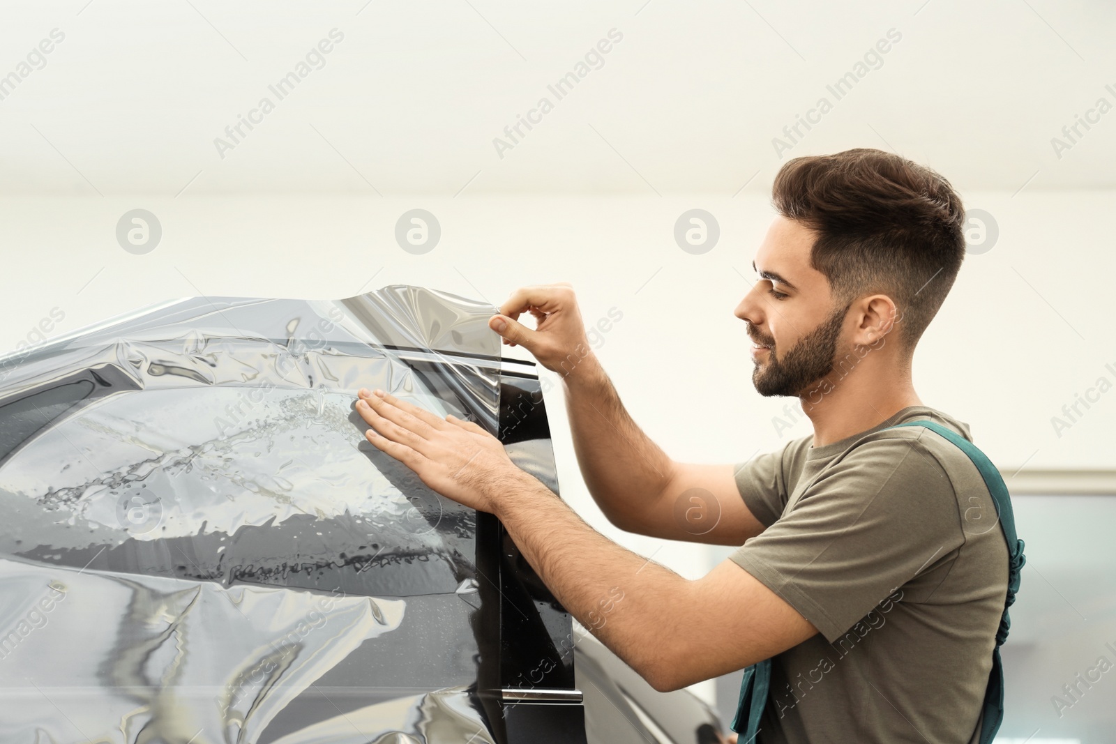 Photo of Worker tinting car window with foil in workshop