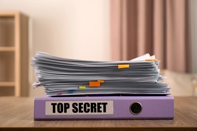 Top Secret stamp. Stacked documents and folder on wooden table indoors