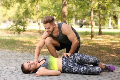 Photo of Man checking pulse of unconscious woman outdoors
