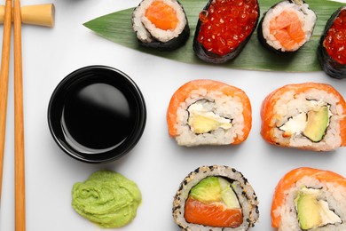 Set of delicious sushi rolls on white background, flat lay