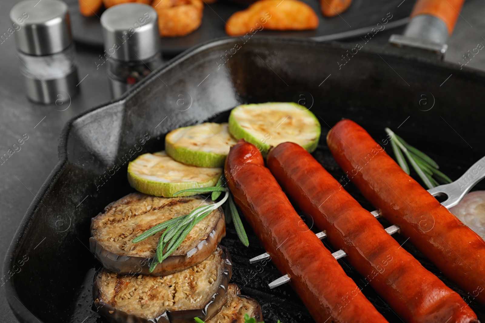 Photo of Delicious grilled sausages and vegetables on grey table, closeup