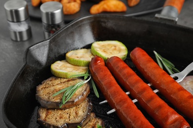 Delicious grilled sausages and vegetables on grey table, closeup