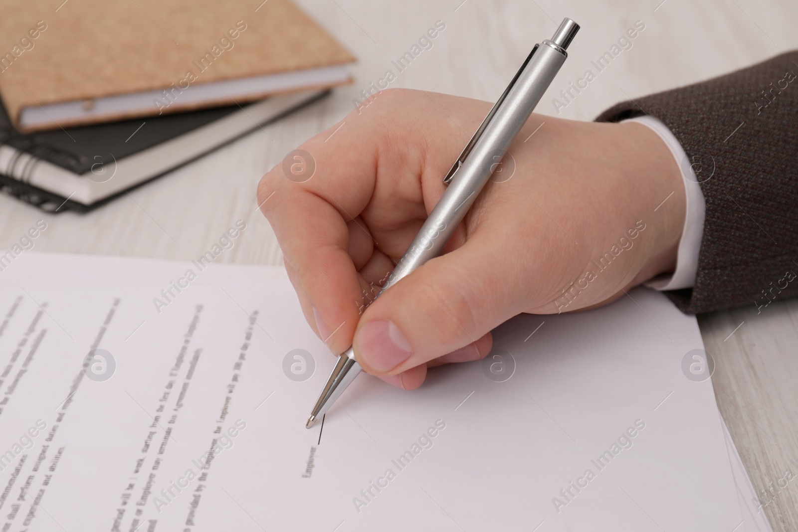 Photo of Man signing document at wooden table, closeup