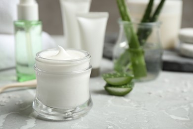 Open jar of aloe cream on grey marble table. Organic cosmetics