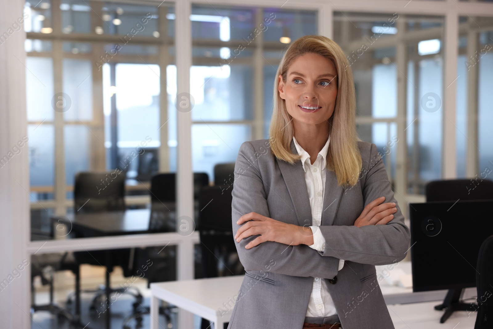 Photo of Smiling woman with crossed arms in office, space for text. Lawyer, businesswoman, accountant or manager