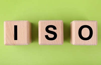 Photo of International Organization for Standardization. Wooden cubes with abbreviation ISO on light green background, top view