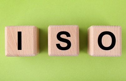 International Organization for Standardization. Wooden cubes with abbreviation ISO on light green background, top view